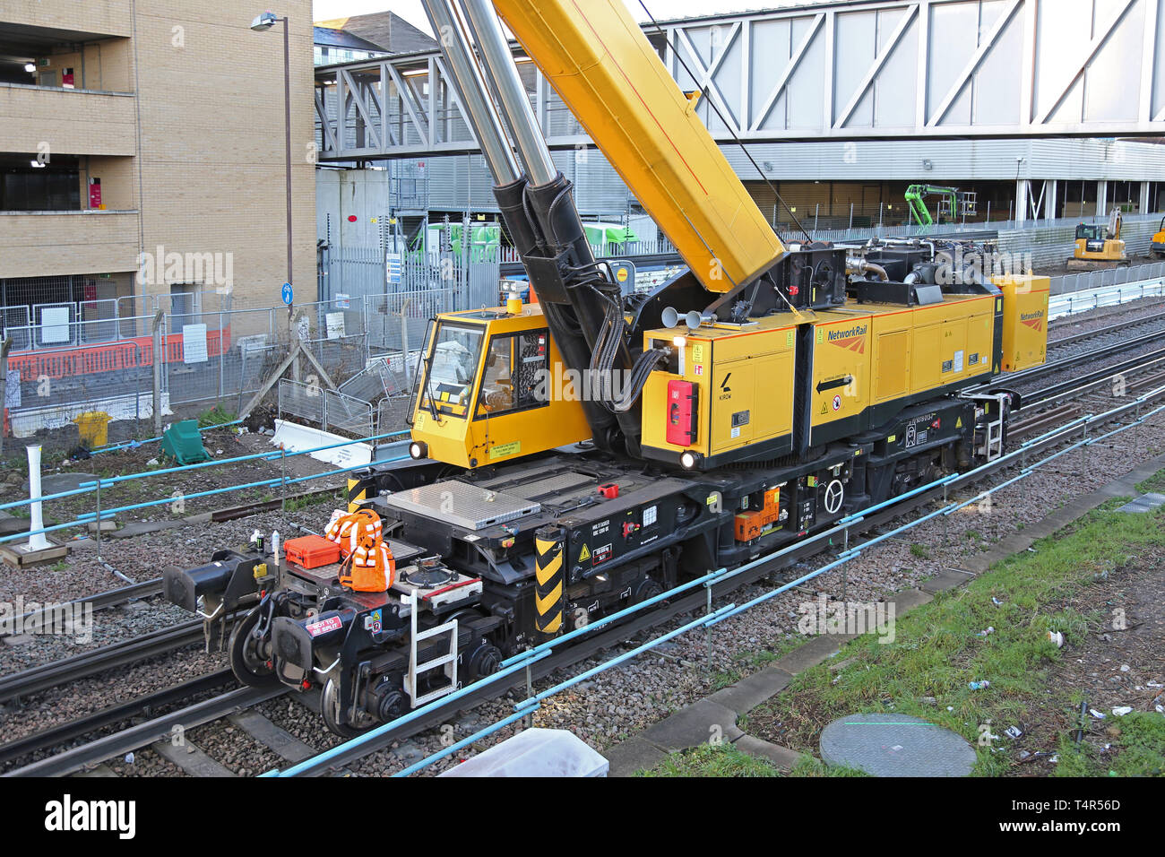 Una ferrovia-montato Kirow gru solleva una impalcatura temporanea passerella in luogo alla Stazione di Feltham, Middlesex durante un weekend di stazione di chiusura. Foto Stock