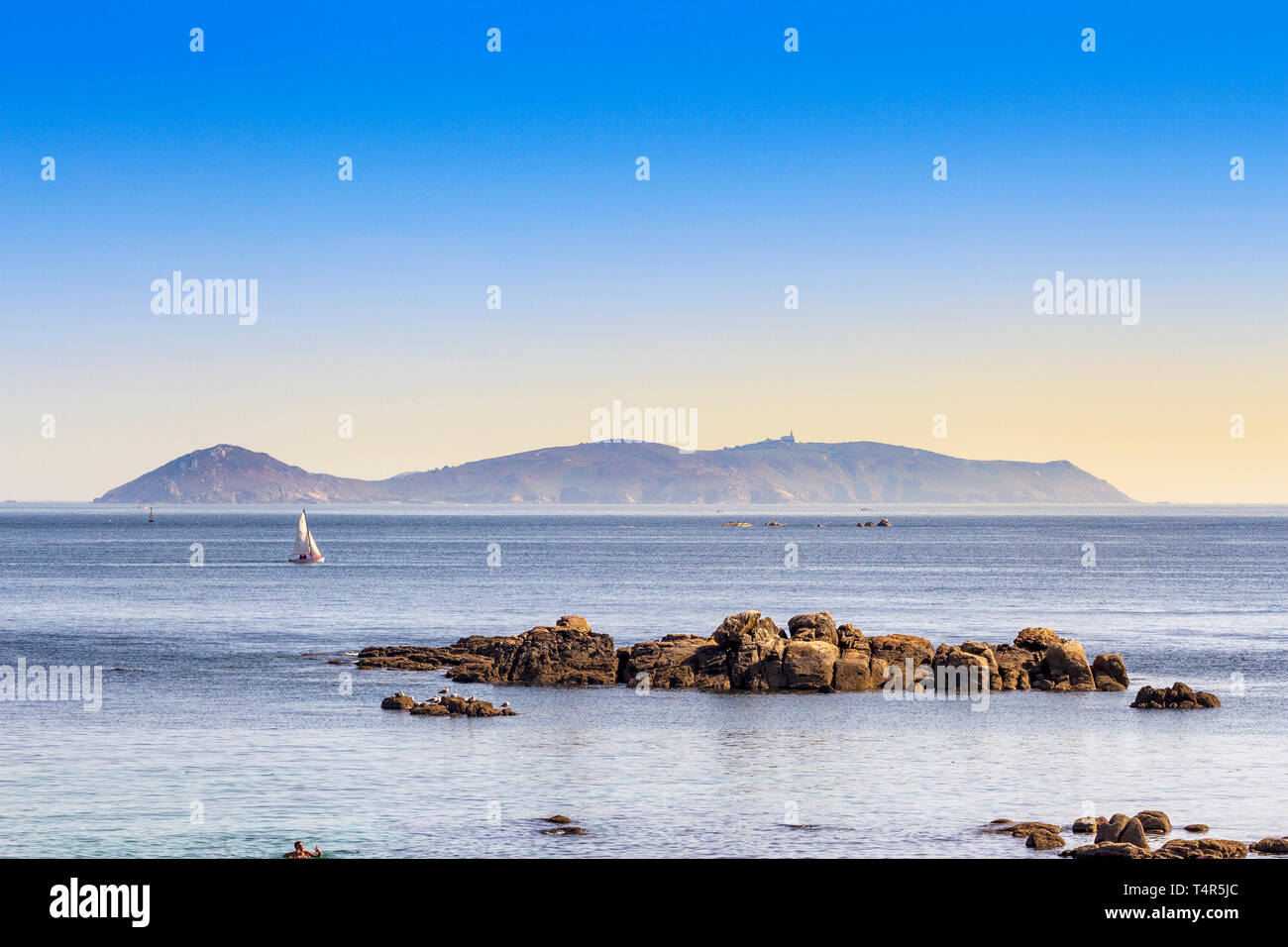 Barca a vela tra Ons Island National Park e isolotto roccioso da San Vicente beach a O Grove città Foto Stock