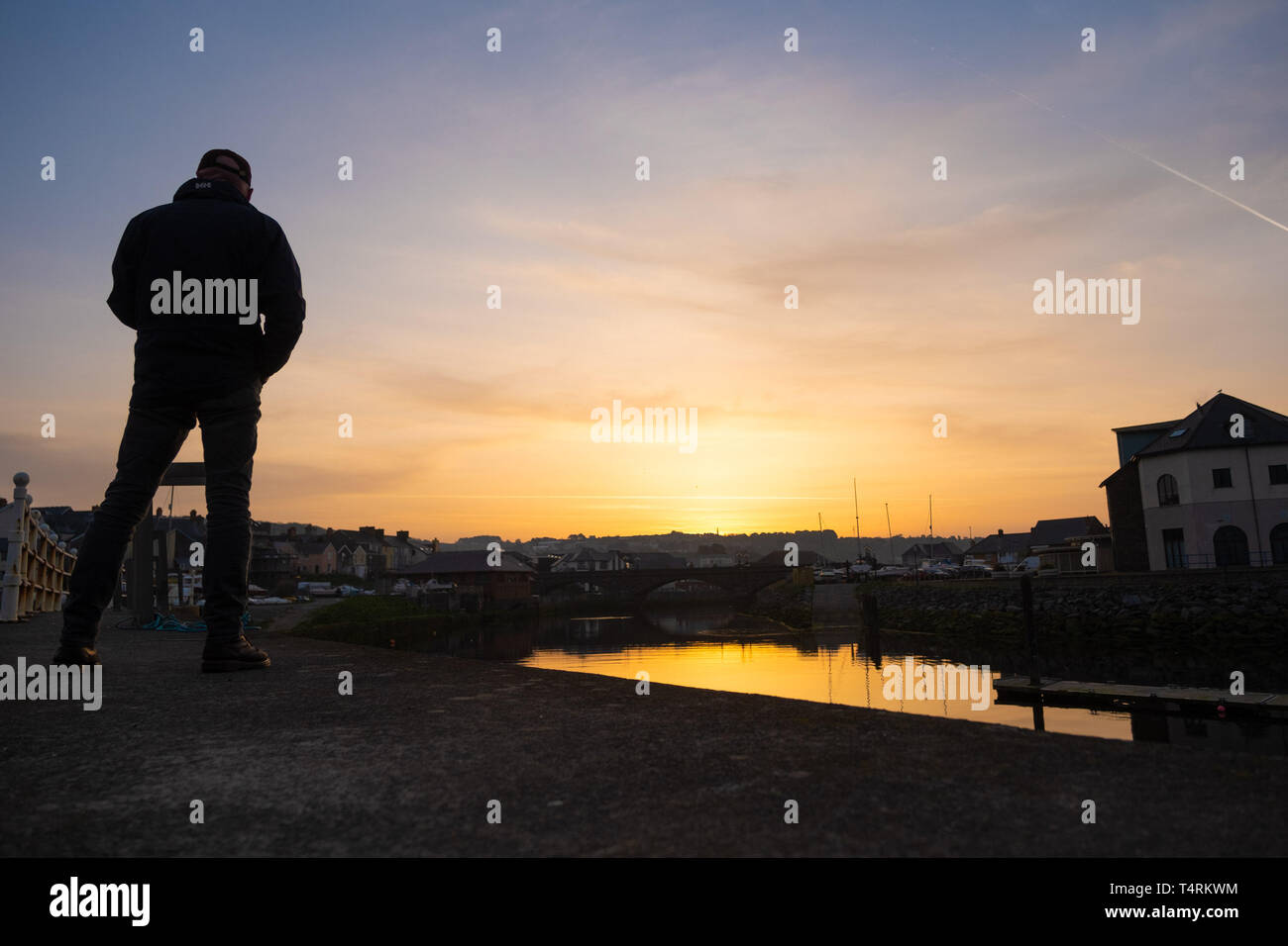 Aberystwyth Wales UK, Venerdì Santo, 19 aprile 2019 UK Meteo: un uomo sta guardando come dawn si rompe sul porto e marina in Aberystwyth sulla West Wales coast all'inizio di quello che promette di essere un glorioso Venerdì Santo, come il paese attende le lunghe vacanze di Pasqua. Temperature in Aberystwyth sono attesi a picco in bassa 70's Fahrenheit oggi, rendendola più calda di molti luoghi in Europa continentale Credito Foto : Keith Morris / Alamy Live News Foto Stock