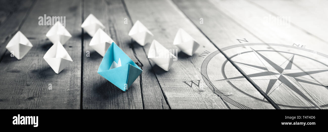 Carta blu barca che conduce una flotta di piccole barche bianco sul tavolo in legno con effetto vintage - Concetto di Leadership Foto Stock