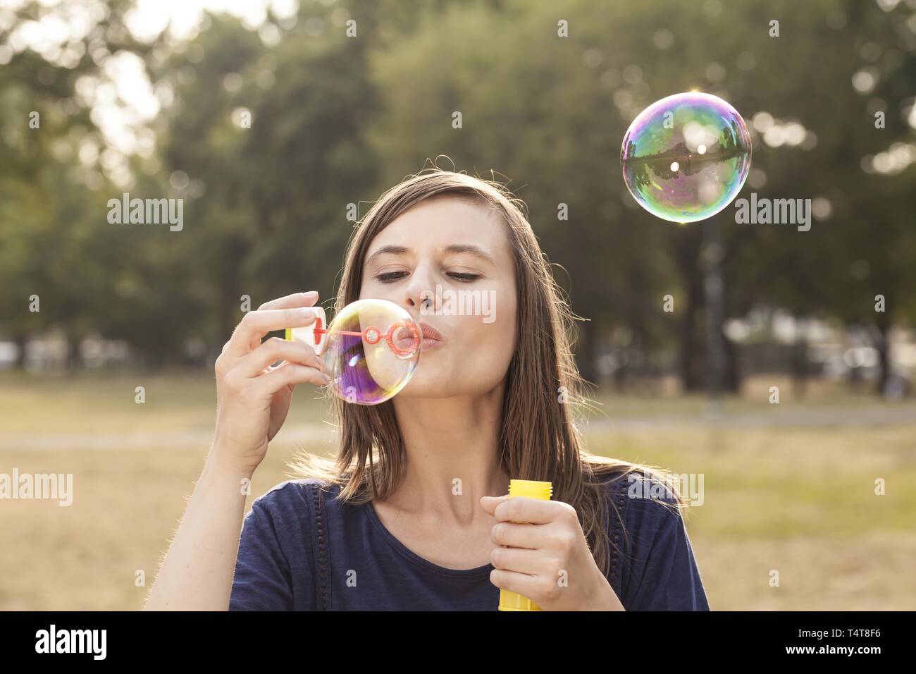Giovane donna fare bolle di sapone, Germania Foto Stock