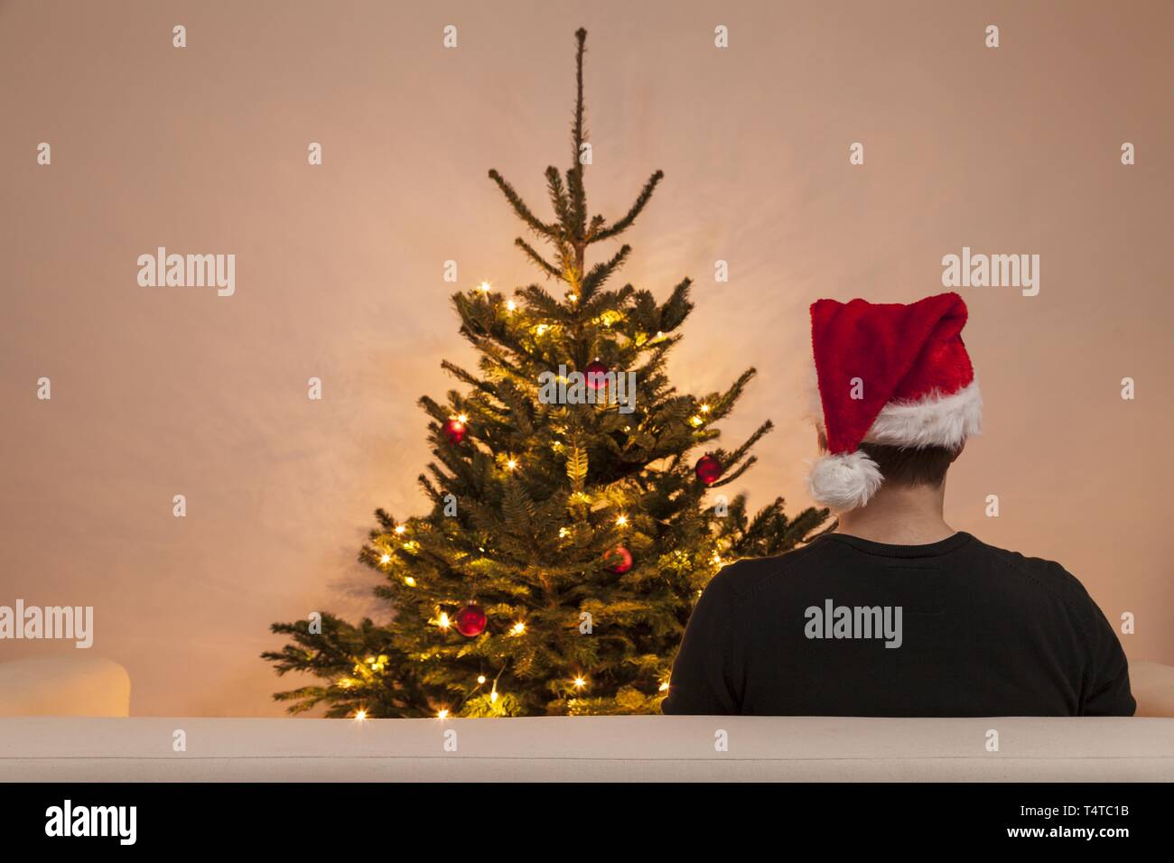 Un uomo seduto su un divano davanti a un albero di Natale Foto Stock