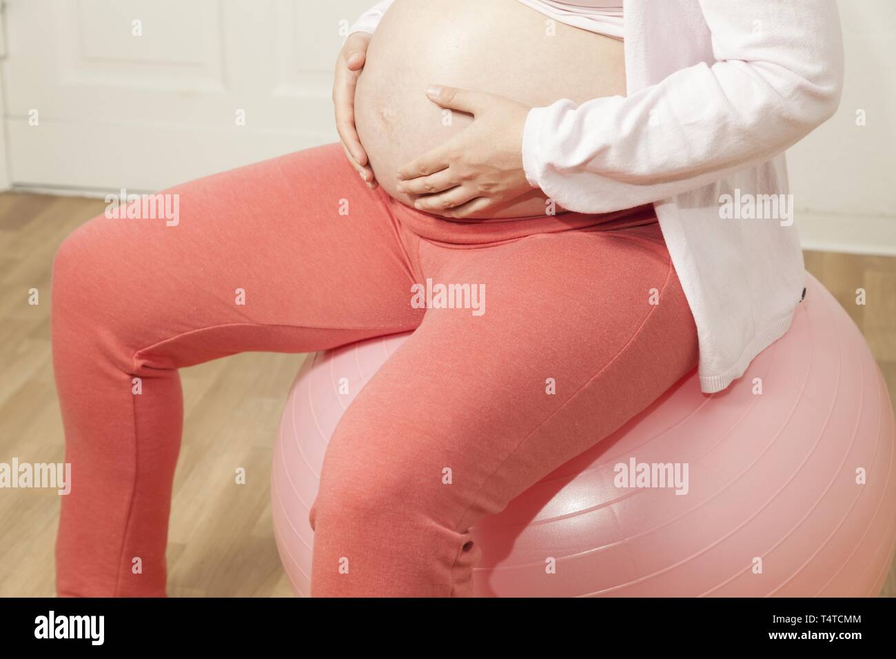 Donna incinta seduta su una palla ginnica Foto Stock