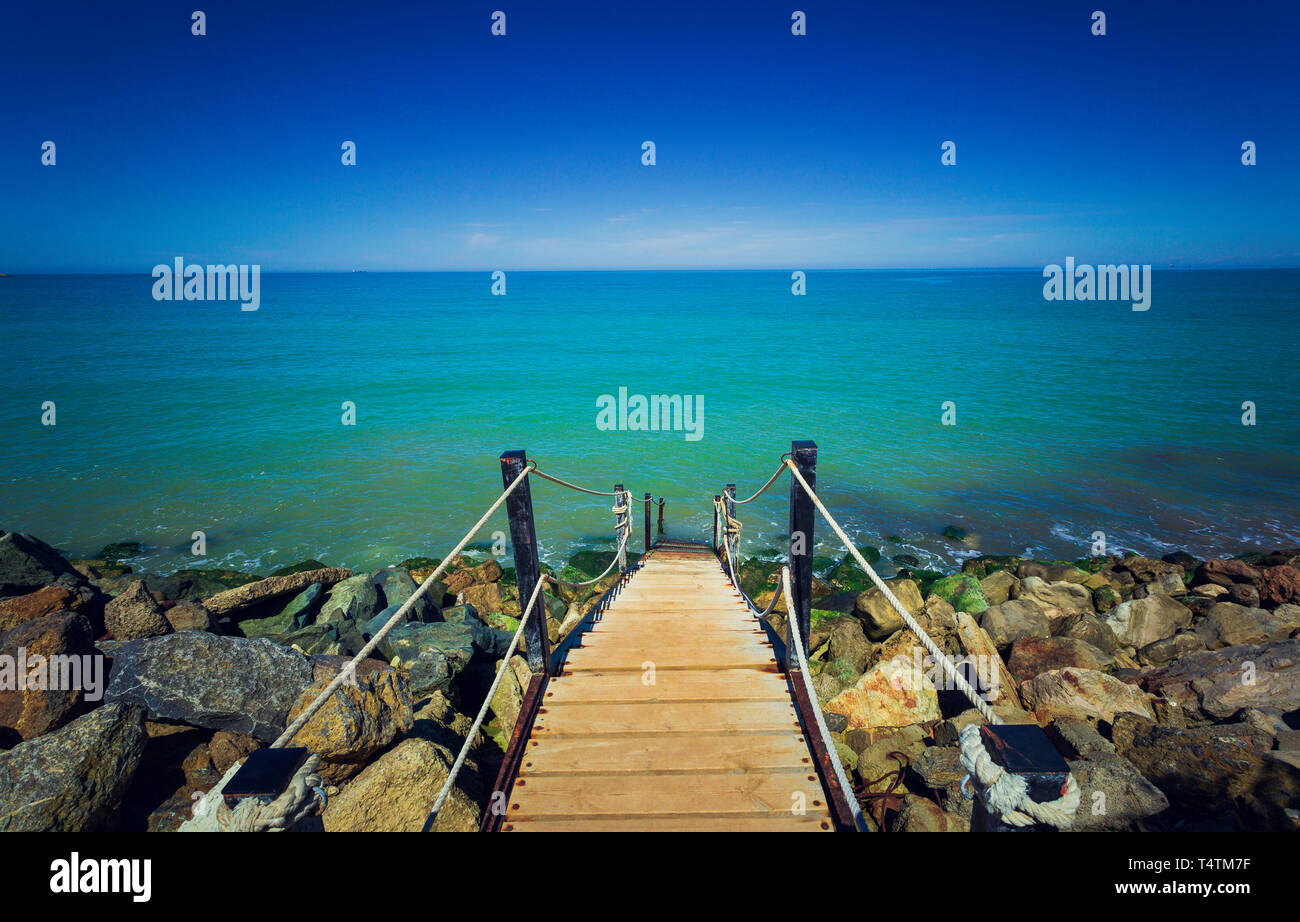 In legno e scale in ferro con corda ringhiere per le acque turchesi nel mare Mediterraneo, Chipiona (Andalusia) Foto Stock
