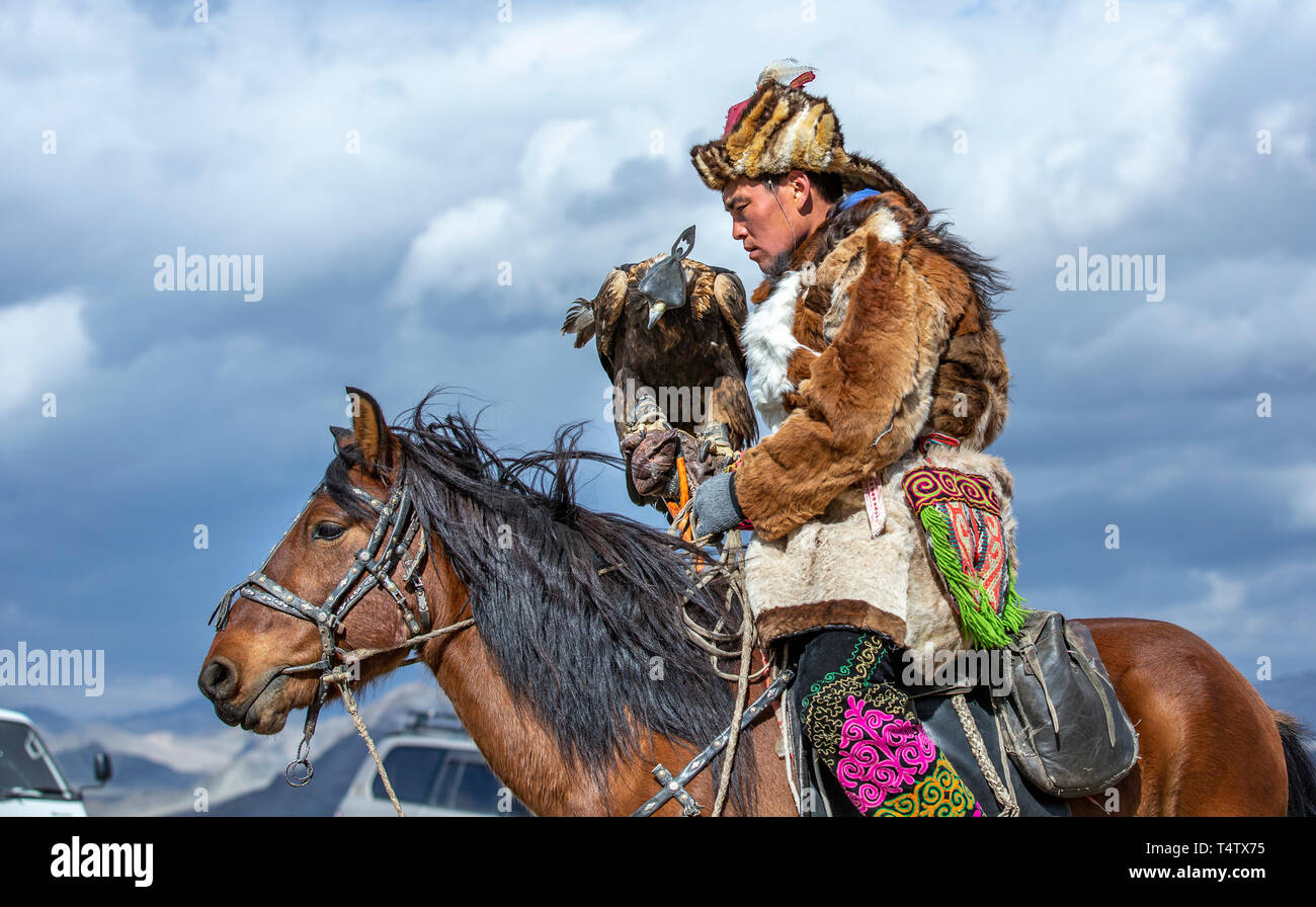 Il bayan Ulgii, Mongolia, 3 ottobre 2015: uomo kazako in tradizionale soprabito e il cappello con il suo eagle su un cavallo Foto Stock