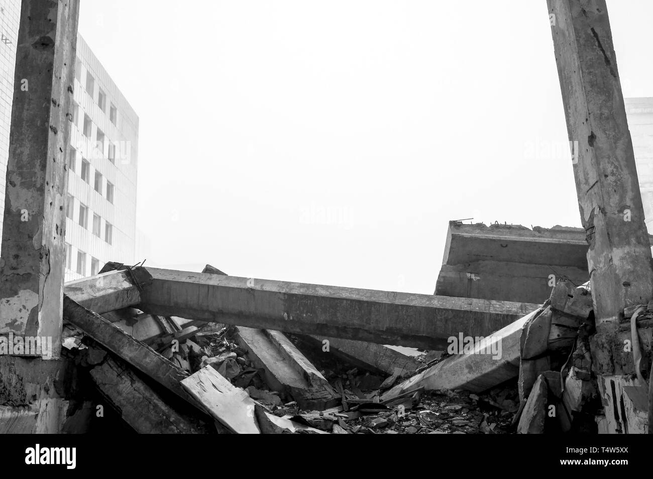 Distrutto il grande edificio in cemento in una nebbiosa opacità. I resti del telaio grigio di pali in calcestruzzo ed i detriti della struttura dell'edificio. Sfondo. Foto Stock