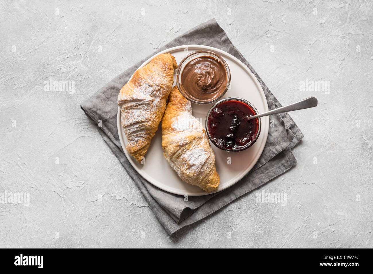 Croissant appena sfornati con marmellata di frutti di bosco su sfondo grigio. Vista dall'alto. Foto Stock