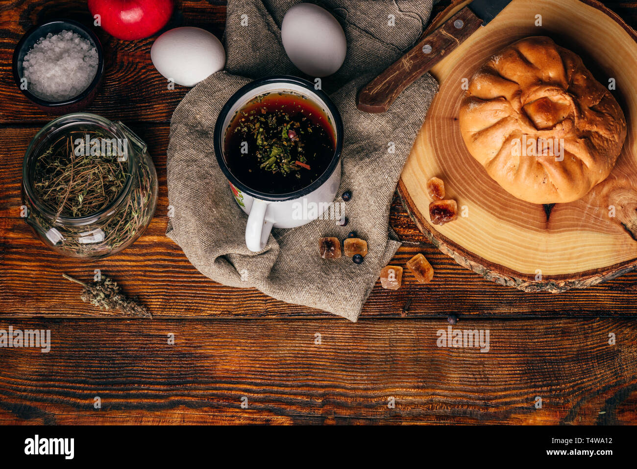 La colazione in stile rustico con tradizionale pasticceria tartara elesh, tè alle erbe in metallo mug, apple e uova sode scuro su una superficie di legno Foto Stock