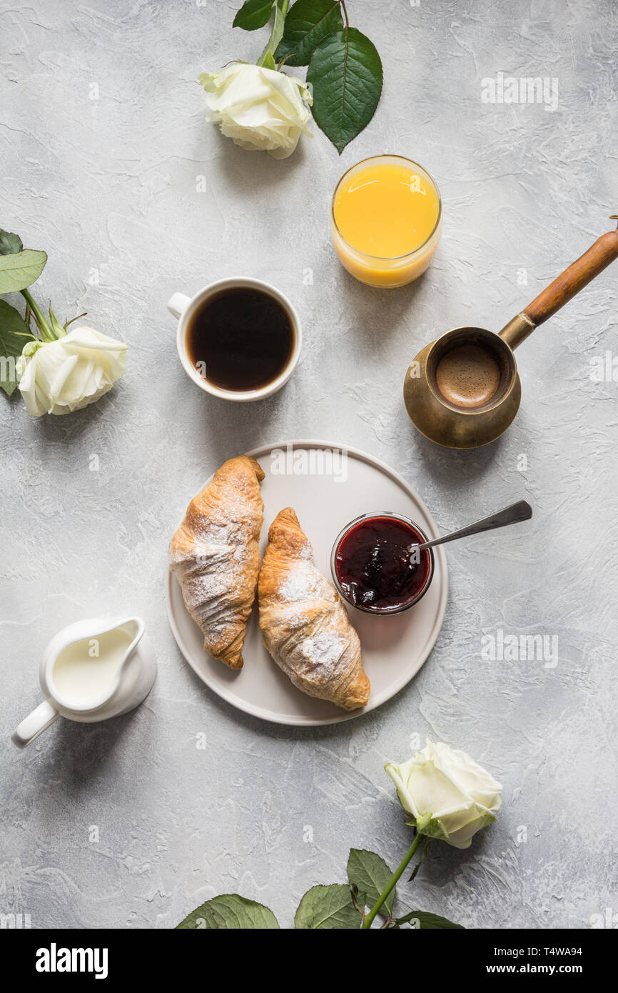 Concetto prima colazione francese. Tazza di caffè, romantica Bianca Rose e i croissant appena sfornati. Vista dall'alto. Foto Stock