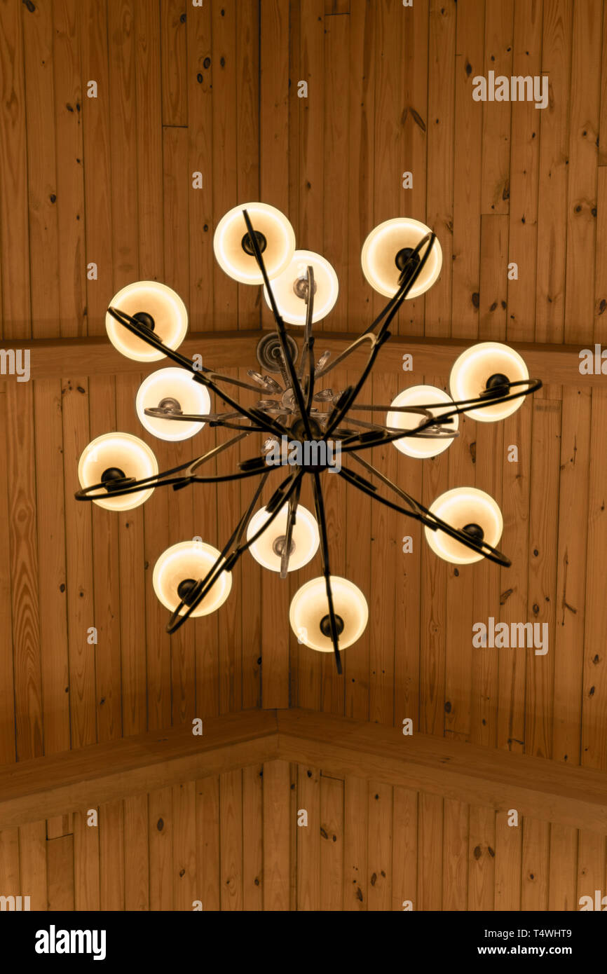 Guardando dritto fino a un ferro battuto lampadario appeso ad una trave di legno sul soffitto Foto Stock