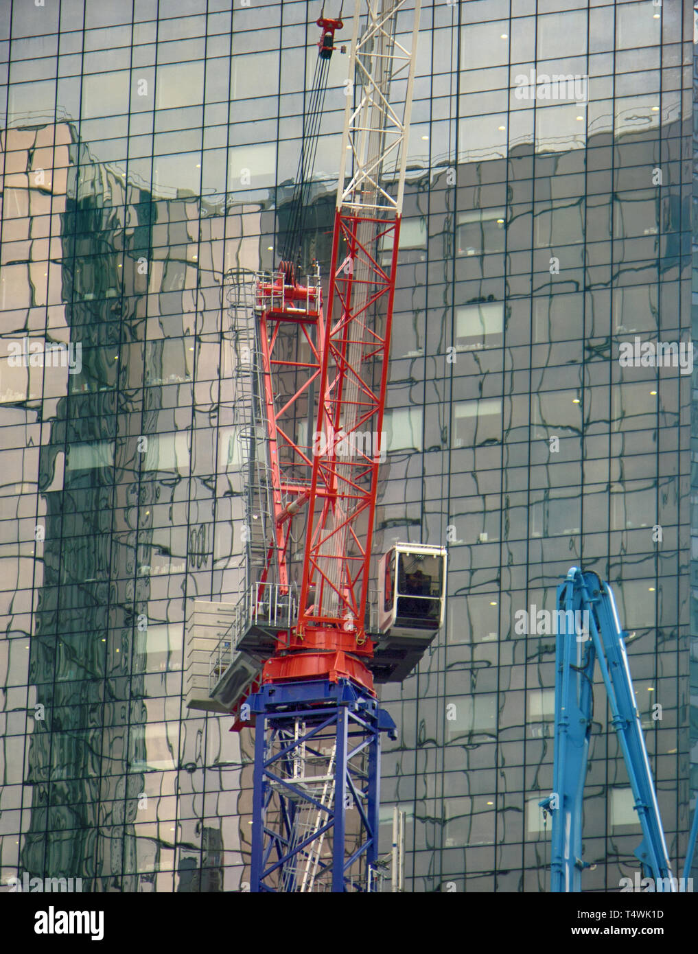 Costruzione, gru da cantiere e costruzione di riflessione a specchio finestre. Defans al tramonto del tempo con alti edifici e alto edificio, sede di bi Foto Stock