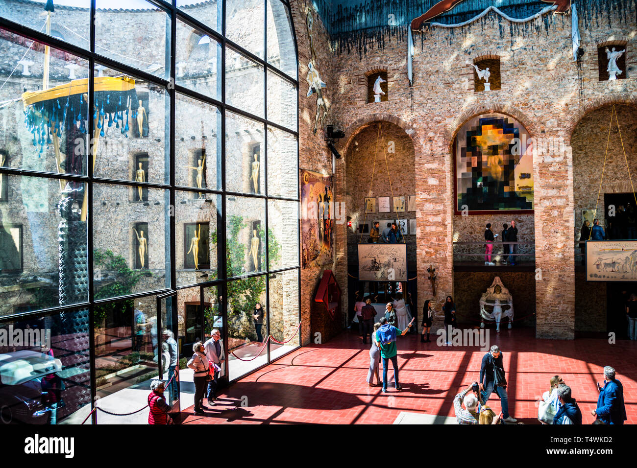 Attraverso la facciata in vetro della sala principale del Teatro-Museo Dalí a Figueres, in Spagna, si può vedere l'installazione "Taxi sotto la pioggia" nel cortile. I visitatori passeggiano sul pavimento in pietra rossa dell'ex palco, dove è sepolto Salvador Dalí. Foto Stock