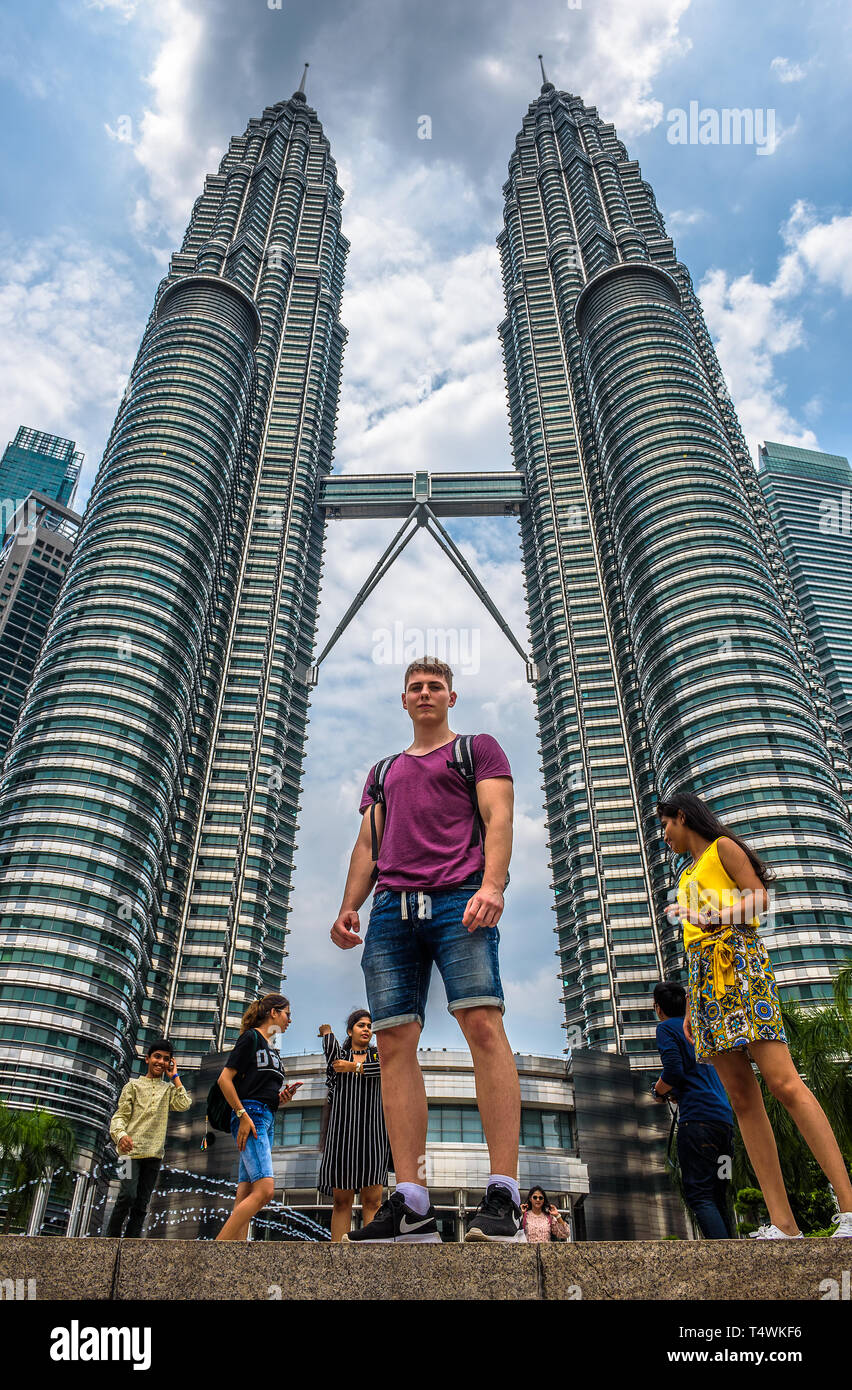 Giovani turisti in piedi sotto le Torri Petronas di Kuala Lumpur in Malesia Foto Stock