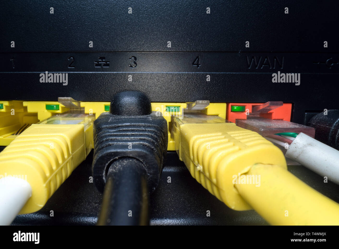 Rete multicolore cavi inseriti nel pannello del router su uno sfondo scuro. Connessione internet, industria di comunicazione Foto Stock