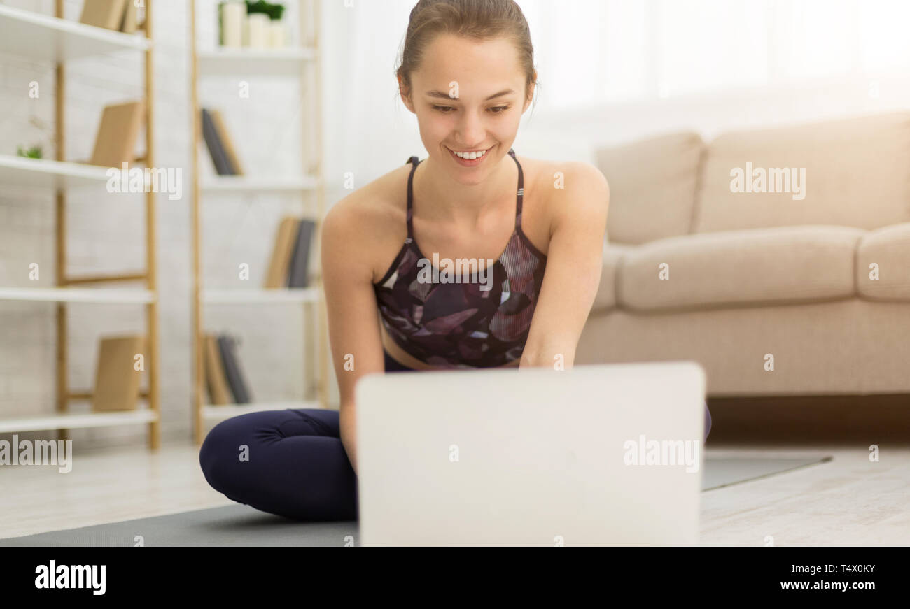 Ragazza farfalla facendo stretching e guardando lo yoga online video tutorial Foto Stock