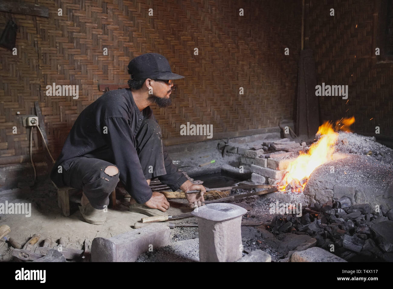 Un fabbro preparare il fuoco con i tradizionali strumenti per rendere Keris Giavanesi arma tradizionale Foto Stock