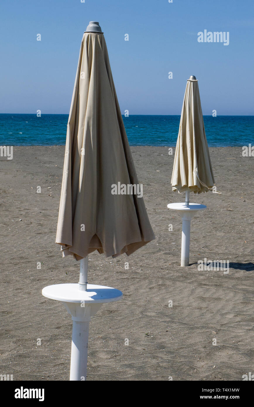 Ombrelloni chiusi, su una spiaggia deserta in inverno Foto Stock