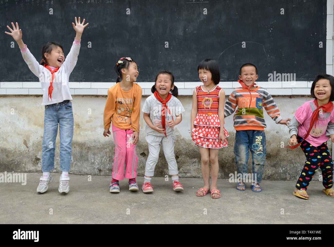 Età primaria scuola bambini saltando e ridendo nel parco giochi scuola rurale nella regione di Guangxi, centrale Cina meridionale. Foto Stock