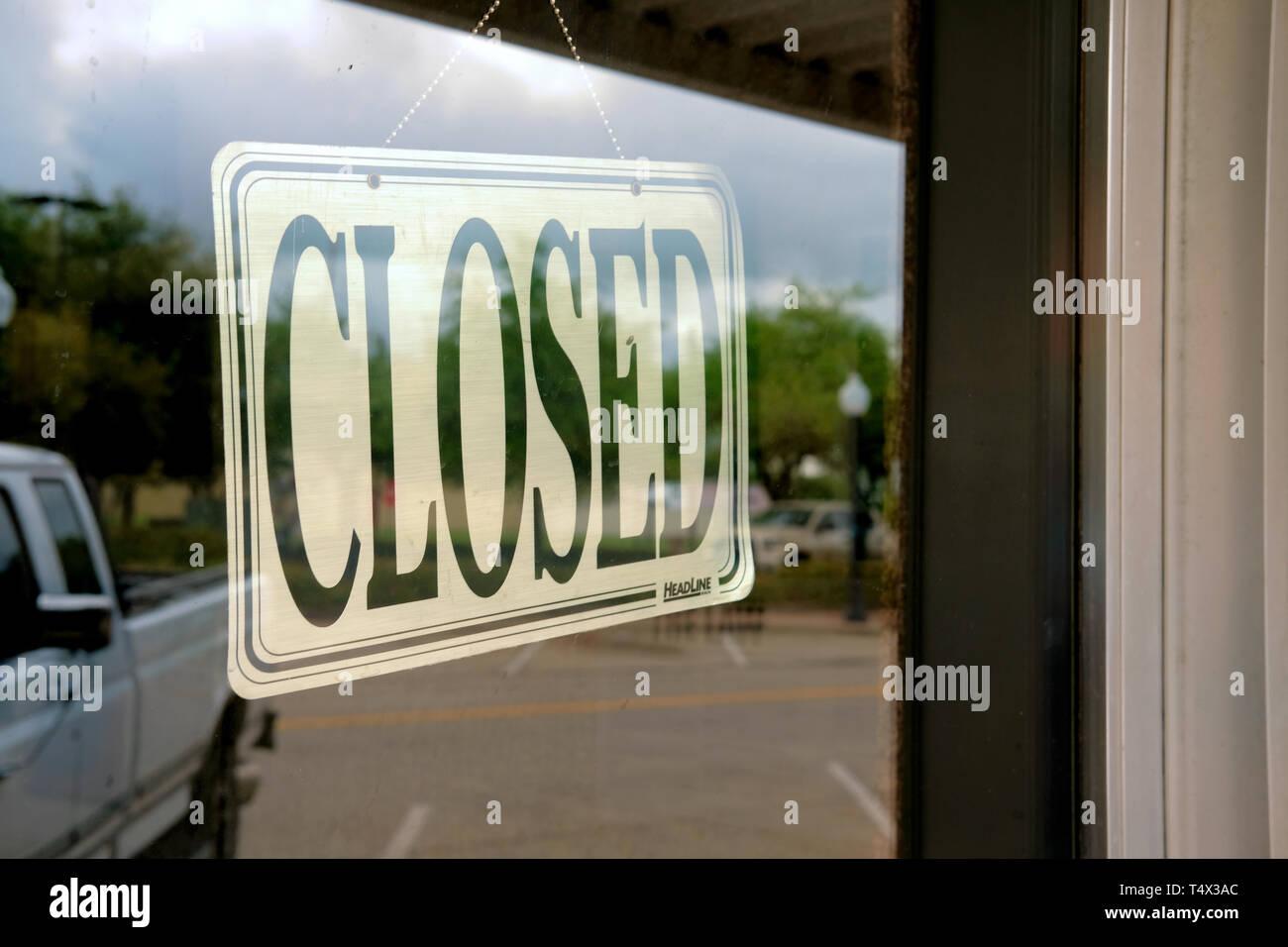 Plastica segno chiuso all'interno di una finestra di vetro in una vetrina in Bryan, Texas, Stati Uniti d'America; la riflessione del carrello parcheggiato sulla finestra. Foto Stock