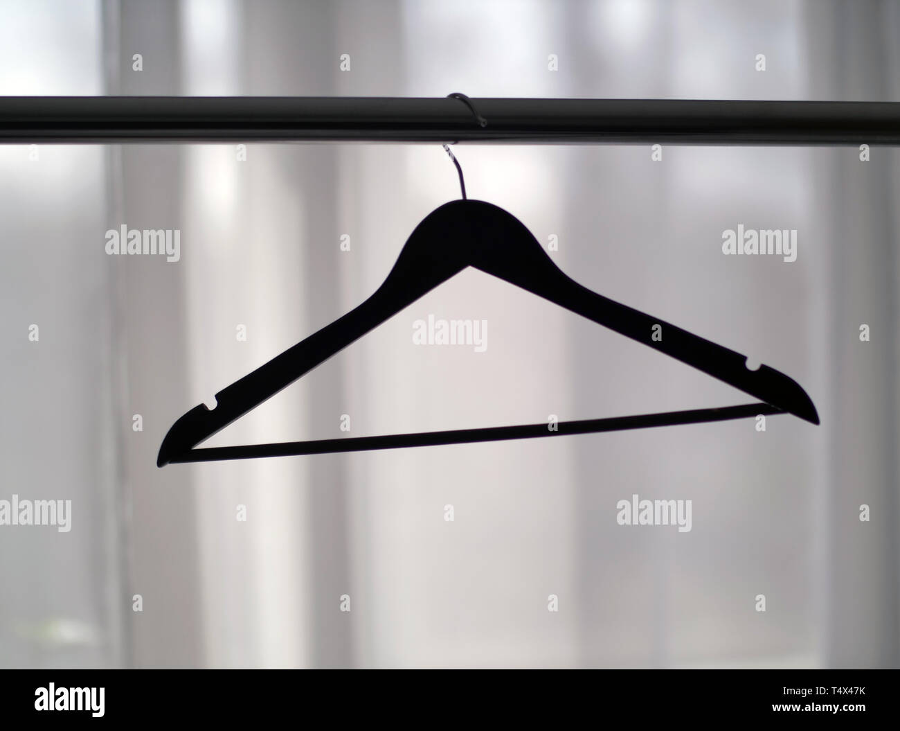 Appendiabiti su una rotaia metallica contro la finestra, close-up Foto Stock