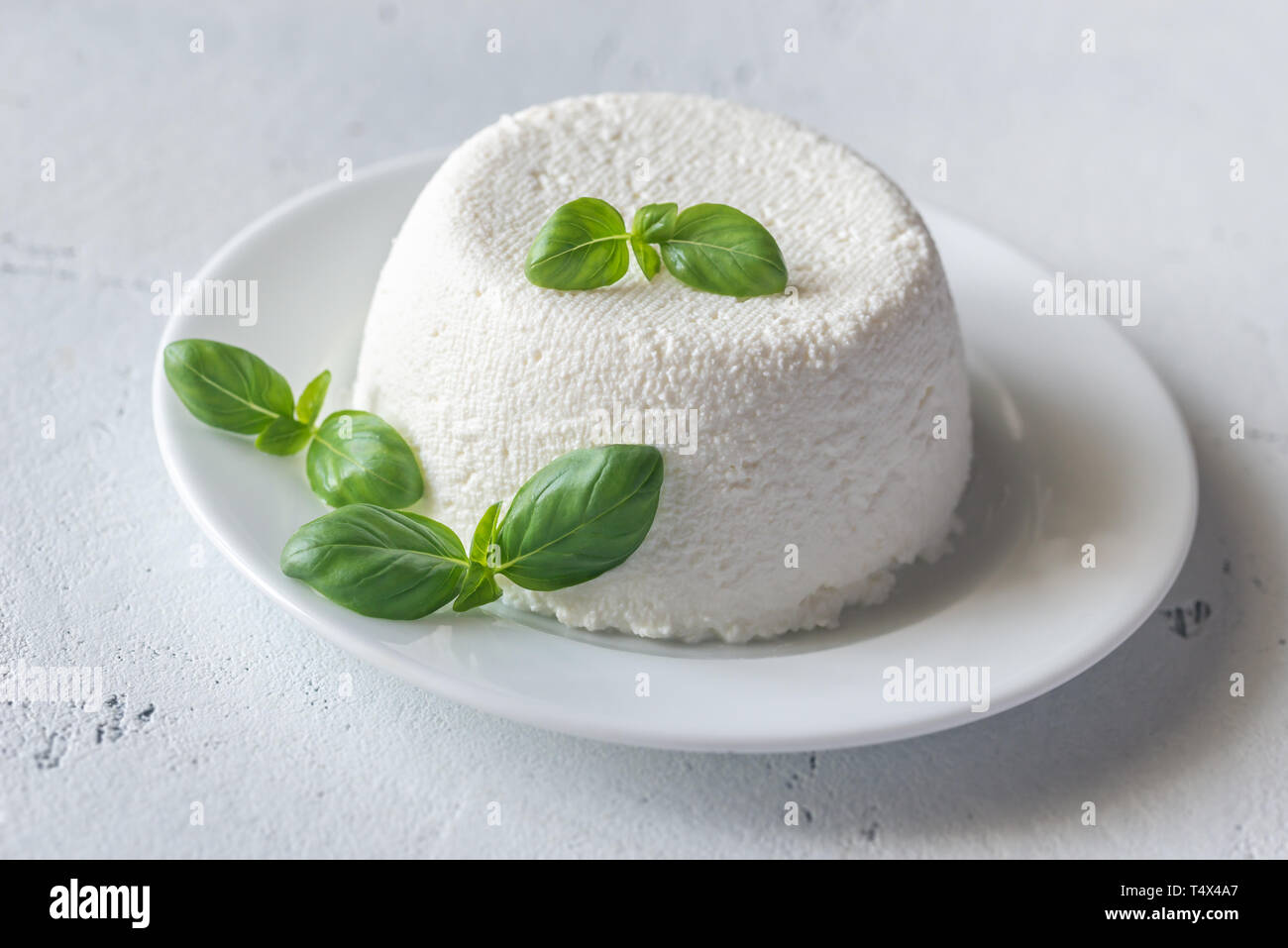 Ricotta - Italiano il formaggio di siero di latte con foglie di basilico fresco Foto Stock