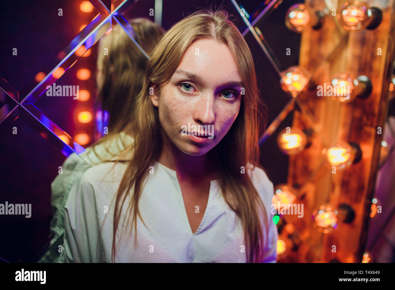 Un ritratto di una bella donna che indossa abiti classici e posa su un muro di mattoni in studio. Bellezza e moda. Foto Stock