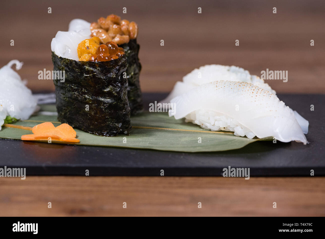 Piastra composta di calamari e seppie sashimi, caviale e soia fermentati gunkan, calamari alla griglia il nigiri, guarnita con insalata di daikon e carote Foto Stock