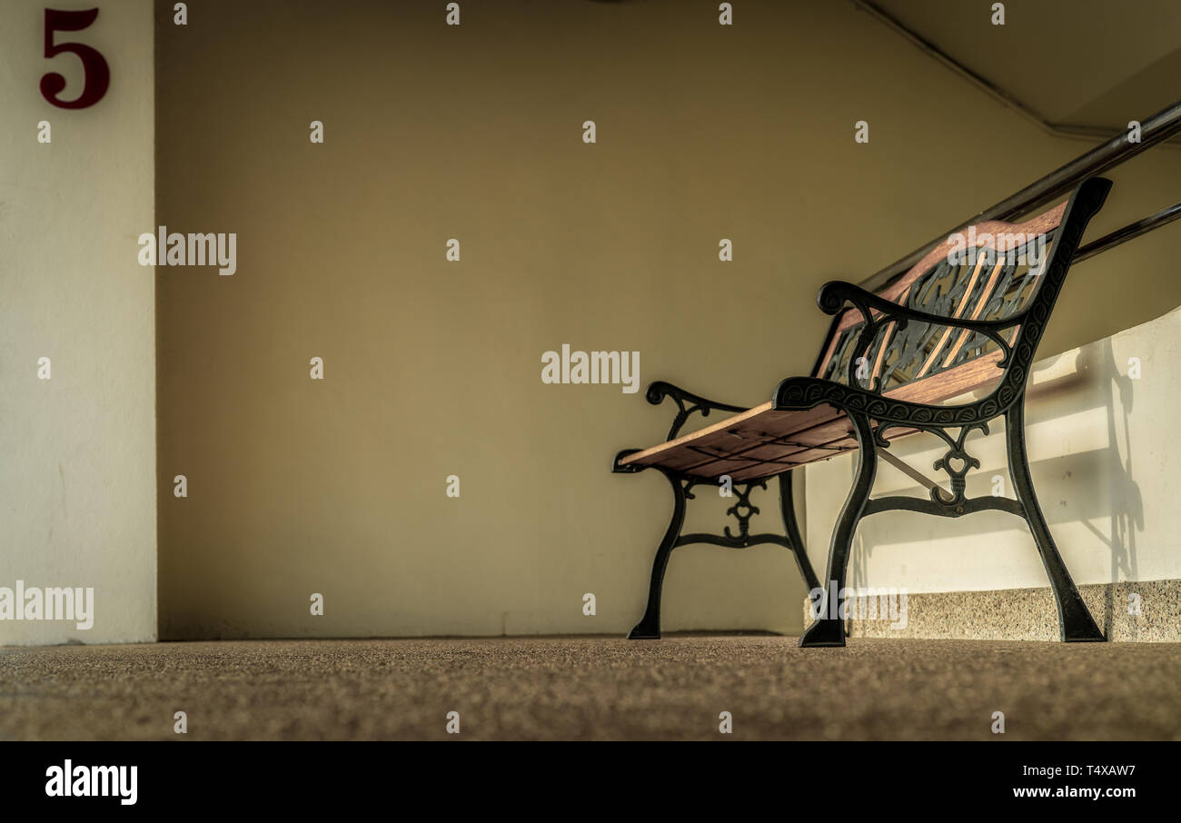 Svuotare il ferro battuto bancone vicino a scale dell'edificio. Premuto, triste e solitaria concetto. Uno vuoto ferro battuto banco. Panca singola Foto Stock