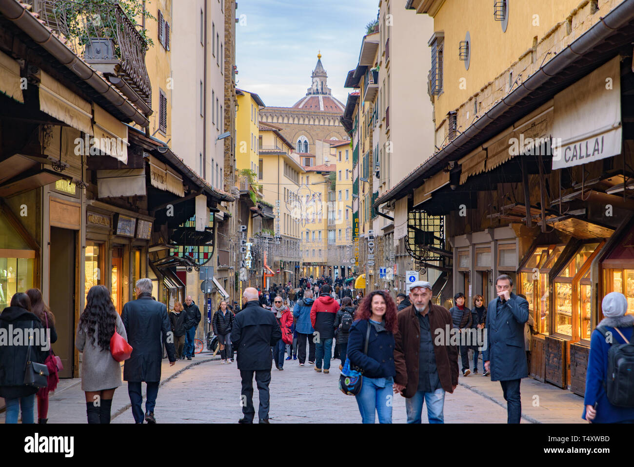 La gente che camminava sul Ponte Vecchio, un medievale ponte in pietra con negozi su di esso, Firenze, Italia Foto Stock
