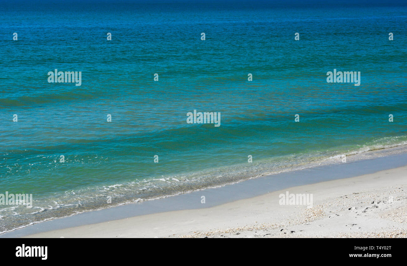 A Strettamente ritagliato seascape vista prevalentemente blu e acque turchesi con molto mite surf lappatura fino ad una spiaggia di sabbia bianca nel sud-ovest della Florida, Stati Uniti d'America Foto Stock