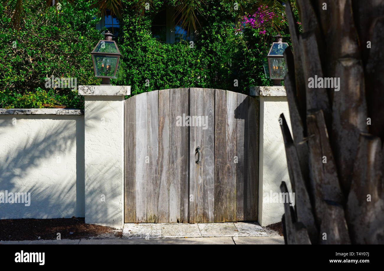 Un affascinante cancello in legno con lanterne in pullman alla sommità di ciascun pilastro, con una graziosa un ambiente tropicale e all'interno di un cortile residenziale in Boca Grande, FL Foto Stock