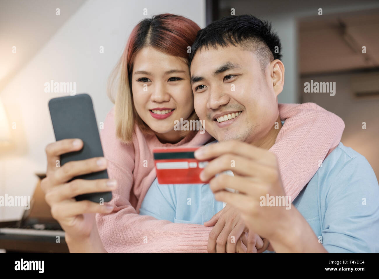 Asian giovane utilizzare mobile shopping online con carta di credito insieme nel salotto di casa.matura nel concetto di casa Foto Stock