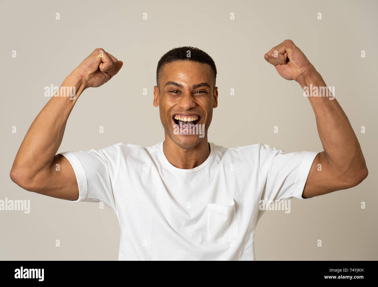 Ritratto di stupiti eccitato african american uomo conseguire il suo obiettivo o wining, ridendo che mostra la vittoria gesto in faccia felice espressione del viso umano, Foto Stock