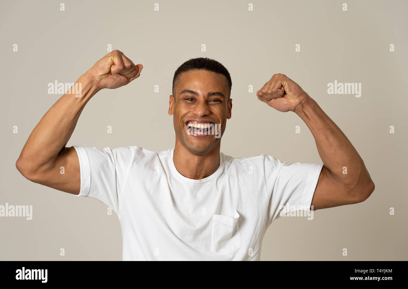 Ritratto di stupiti eccitato african american uomo conseguire il suo obiettivo o wining, ridendo che mostra la vittoria gesto in faccia felice espressione del viso umano, Foto Stock
