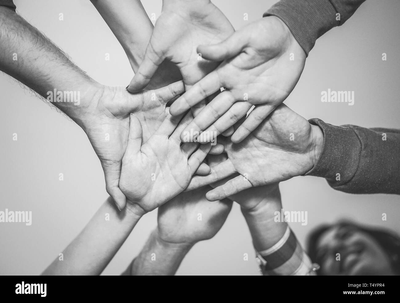 In prossimità dei giovani al lavoro di squadra di mettere le loro mani insieme per una nuova collaborazione - Allegro amici motivato su un piano Foto Stock