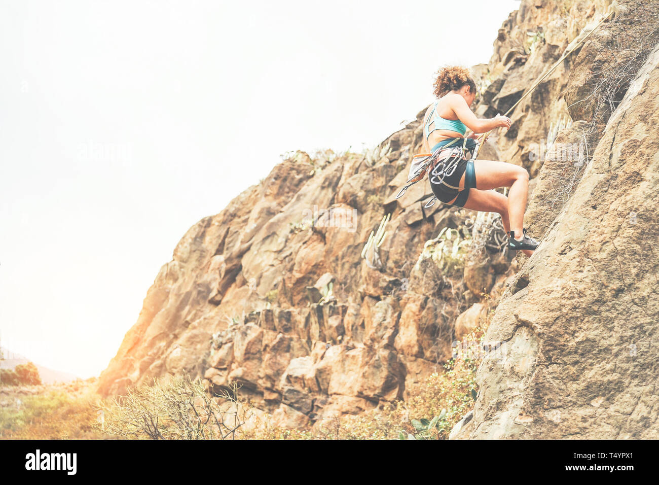 Giovane donna arrampicata su una parete di roccia al tramonto - alpinista sana esecuzione in alta montagna - Concetto di sport, extreme, hobby e stile di vita Foto Stock