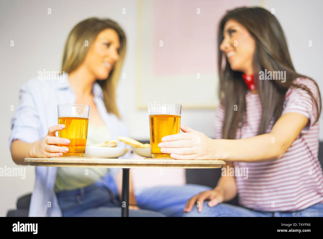 Giovani donne gustando un pasto bere birra e mangiare la pizza a casa - Happy amici divertendosi con un pranzo nel loro appartamento seduto sul divano Foto Stock