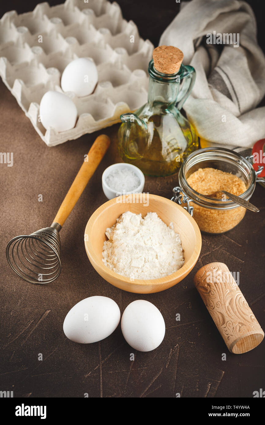 Ingredienti per la cottura pirok o cookie - la farina in una ciotola di legno, uova, burro, cannella, anice e un piccolo legno decorativo mattarello Foto Stock