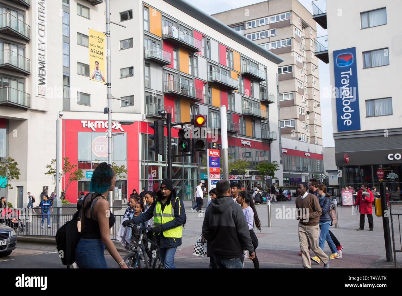 Pedoni che attraversano High Road, Wembley, nella parte anteriore di un moderno shopping e sviluppo di alloggiamento a Wembley Central. Foto Stock