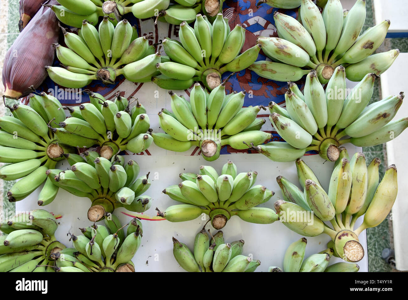 Molti banana acerba gettare sul tavolo per vendere Foto Stock