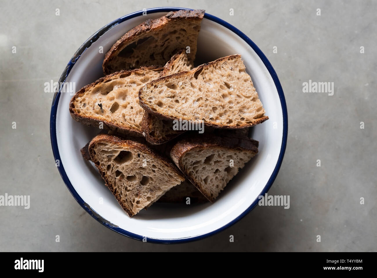 Direttamente sopra il colpo di fette di pane marrone in bianco e blu la coppa di smalto su pietra bancone cucina Foto Stock