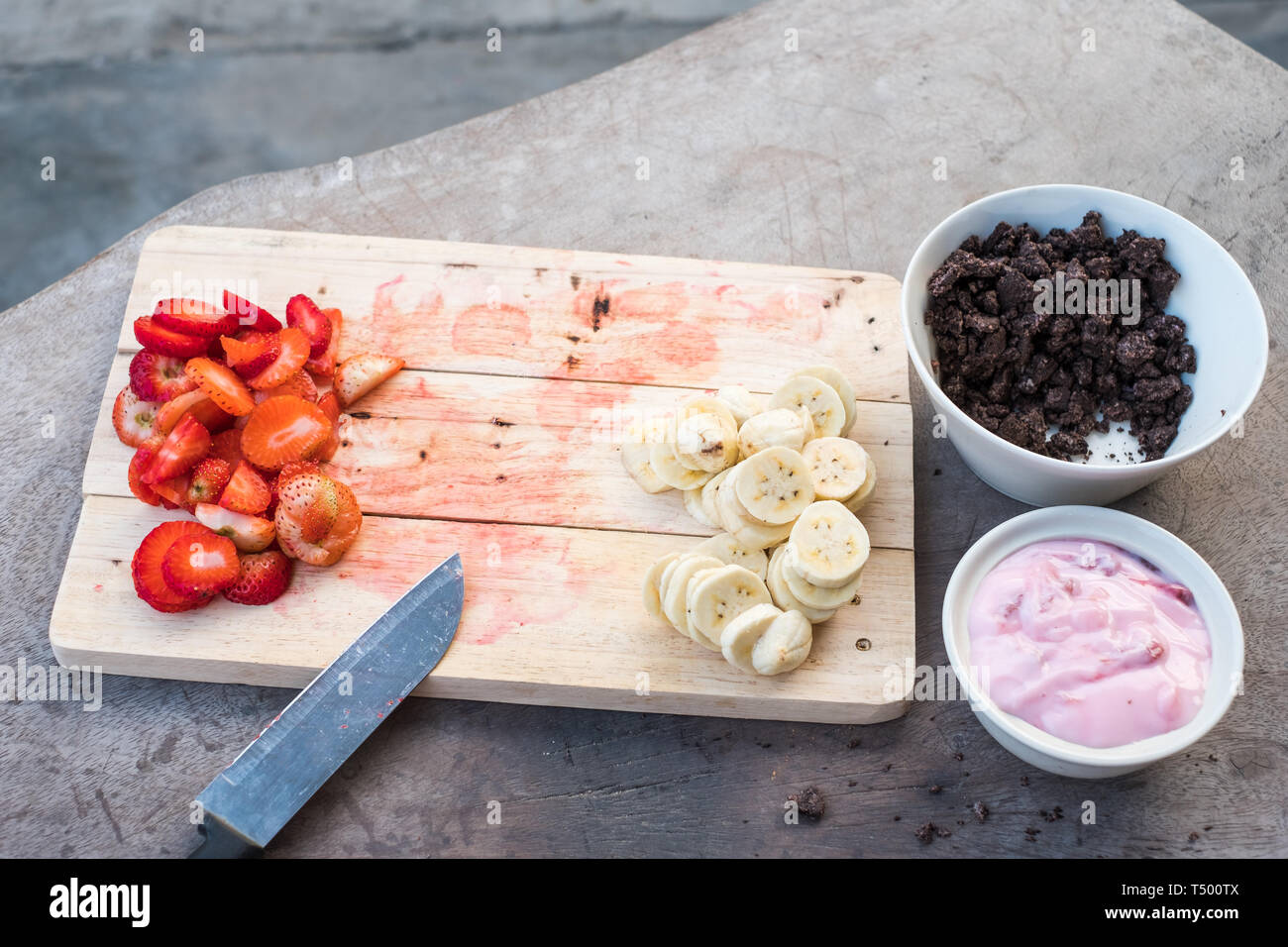 La preparazione di cibo dolce con banana, fragola, cacao e Yogurt sul tavolo di legno Foto Stock