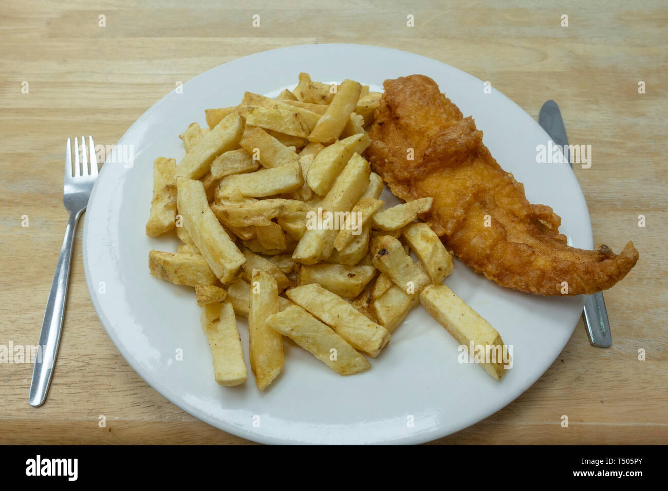 Una piastra di British pesce e patatine fritte su un tipico tavolo del bar, come viene servito in Tenby, Dyfed Galles. Foto Stock