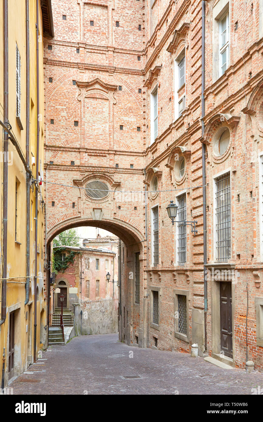 Empty street con mattoni rossi edificio e arco in un giorno di estate a Mondovì, Italia Foto Stock