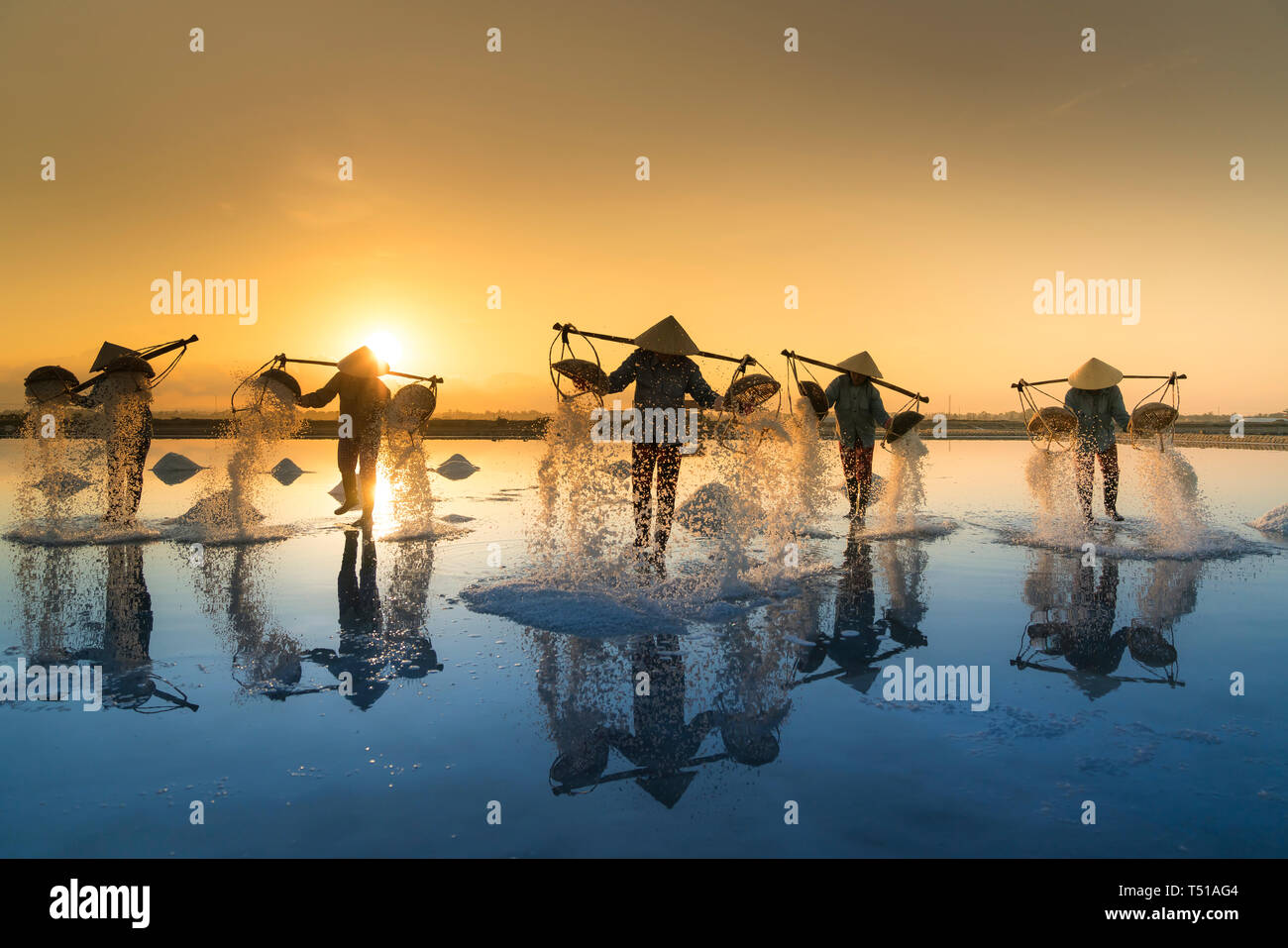 Le donne sono al lavoro sul campo di sale all'alba. Campo sale Hon Khoi a Nha Trang, Viet Nam. Foto Stock