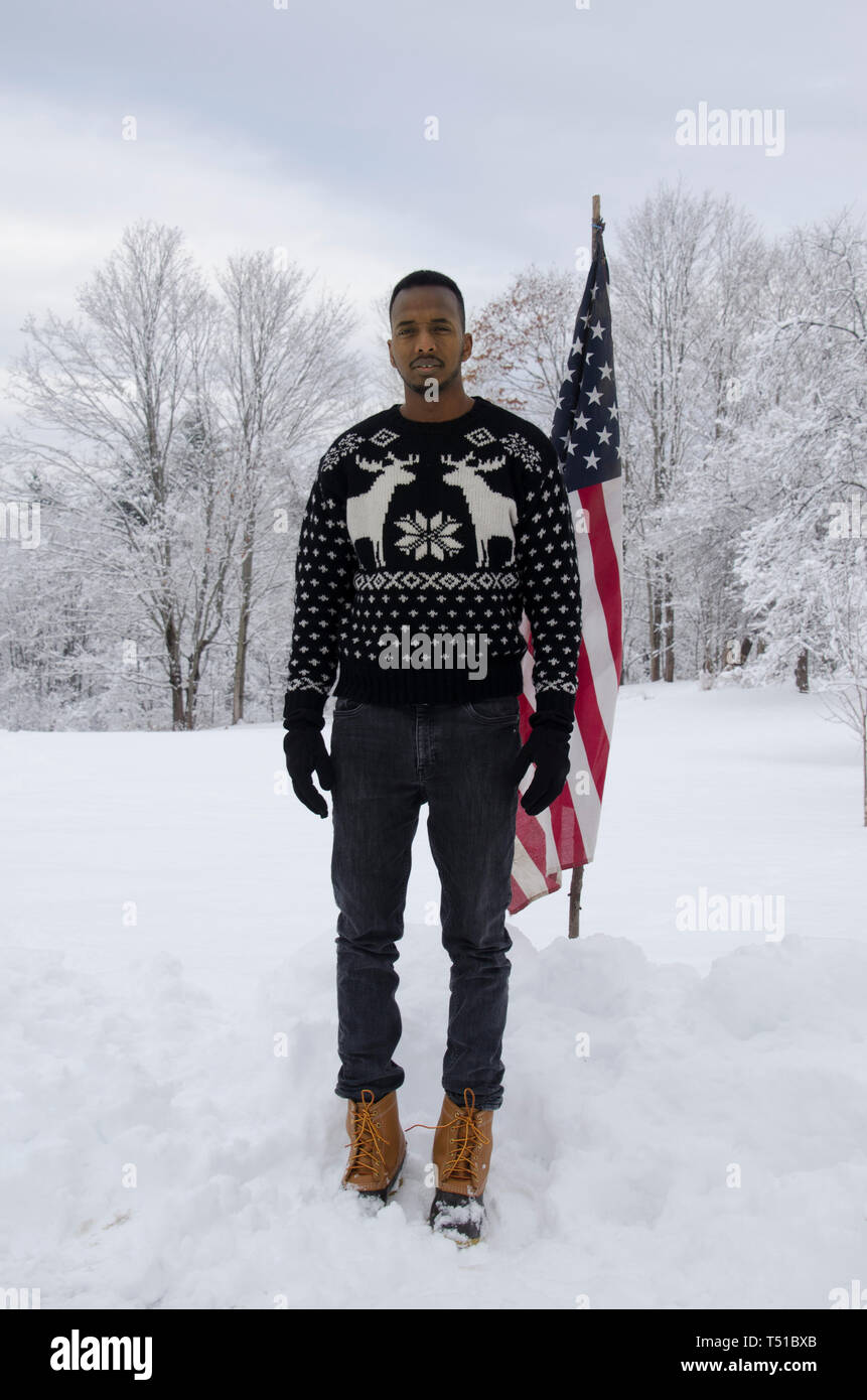 Somala immigrata, Abdi Iftin e autore di "Call me americano', in piedi in campo nevoso con bandiera americana, Yarrmouth Maine Foto Stock