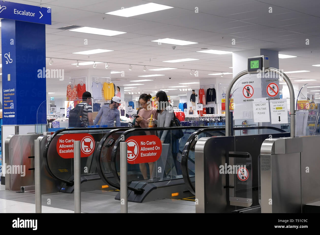 Coquitlam, BC, Canada - 31 Marzo 2019 : il movimento di persone di prendere le scale mobili nei moderni interni urbani all'interno Walmart store Foto Stock