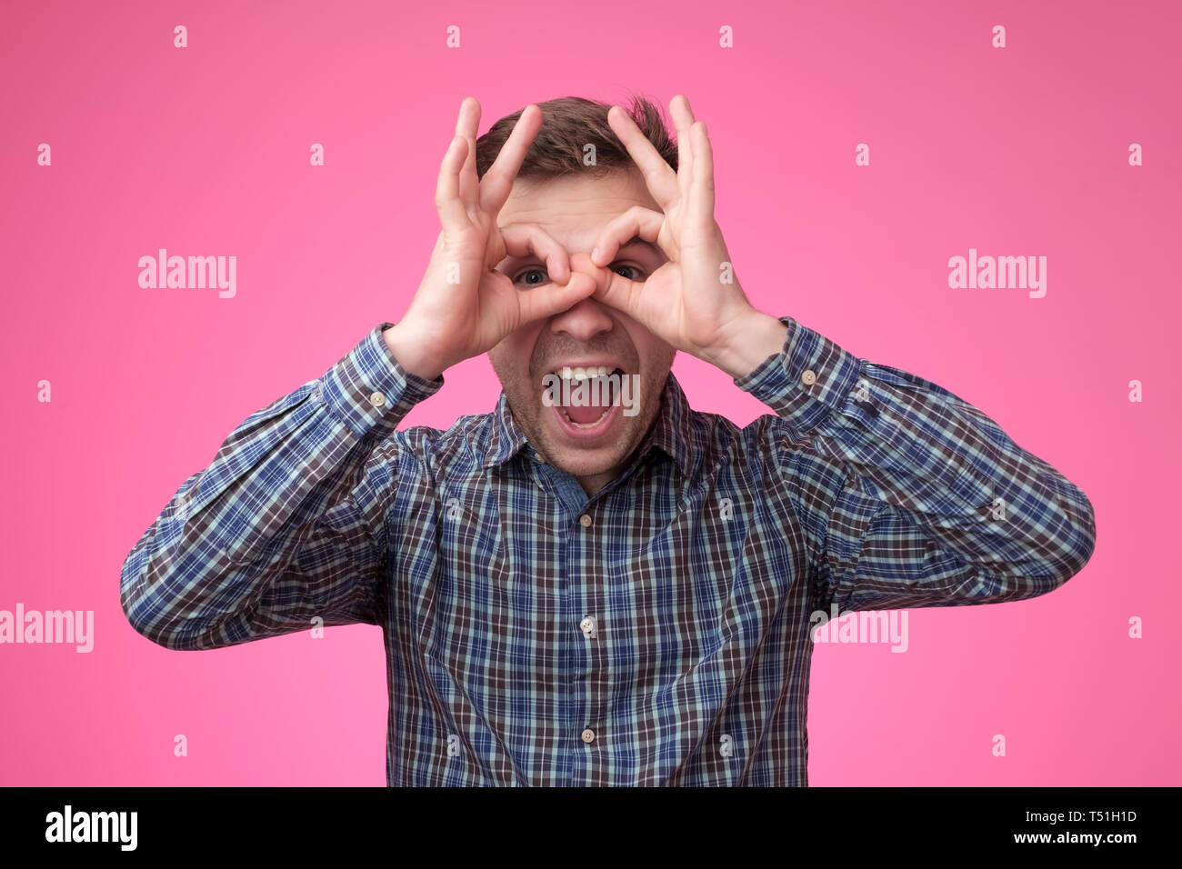 Giovane uomo bello che mostra eroe o gufo segno o simili con gli occhiali Foto Stock