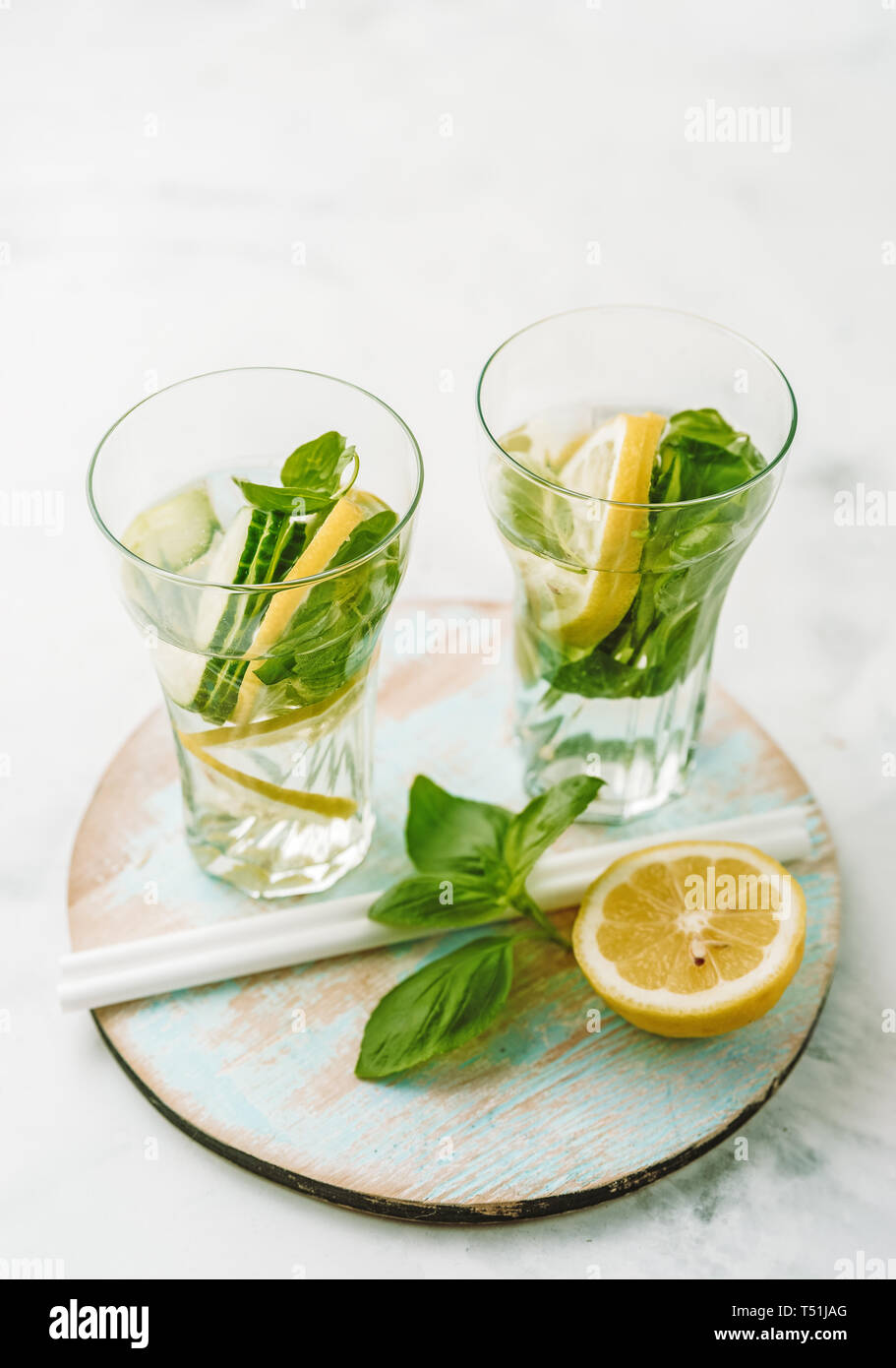 Acqua infusa in due bicchieri con limone, cetrioli e basilico Foto Stock