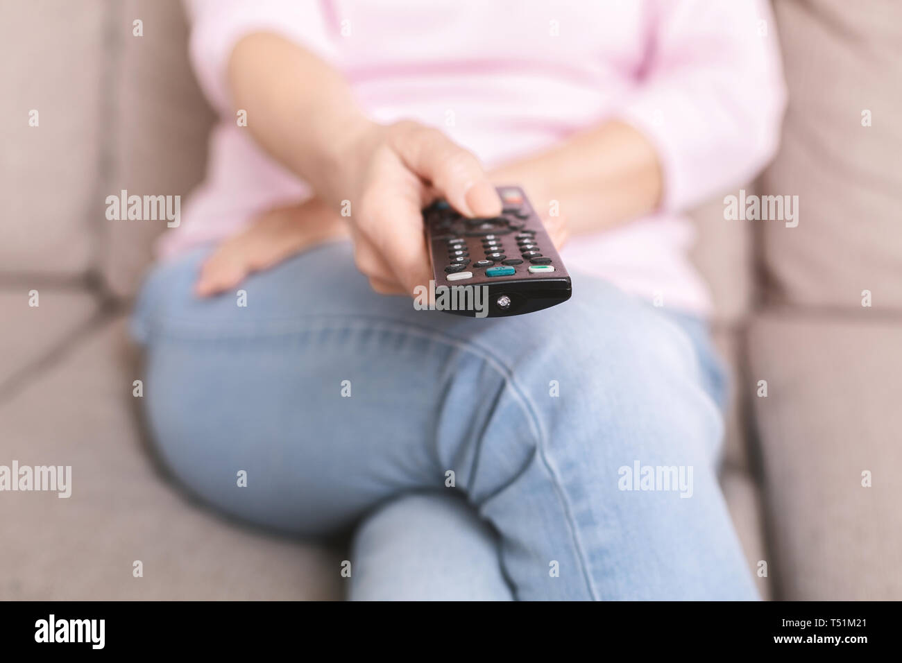 Donna senior di cambiare i canali sul televisore con telecomando Foto Stock